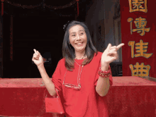 a woman in a red shirt stands in front of a chinese sign