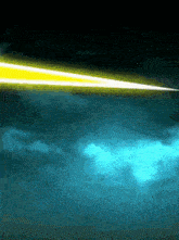 a yellow beam of light is flying through a dark blue sky