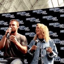 a man and woman are standing in front of a wall that says heroes & villains fanfest
