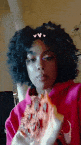 a woman in a pink nike hoodie is eating a slice of pizza .