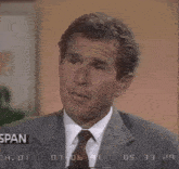 a man in a suit and tie is making a face in front of a screen that says " span "