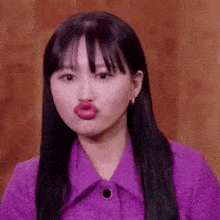 the woman is wearing a purple jacket and making a funny face .