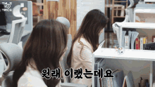 two women sit at a desk in an office with twice written on the top