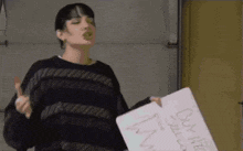 a woman in a black sweater is holding a sign that says " bullying is not okay "