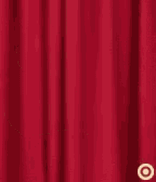 a person in a yellow shirt is giving a thumbs up sign in front of a red curtain .
