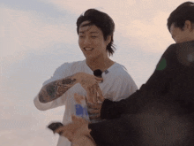 a man with a tattoo on his arm is smiling while another man holds his arm