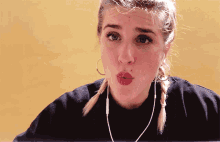 a woman wearing a black shirt and earphones makes a funny face