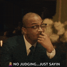 a man wearing glasses and a suit says no judging just sayin