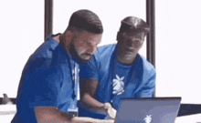 two men are looking at a laptop computer .