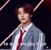 a young man in a suit and tie is standing in front of a microphone and says te amo ale soy tuyo .