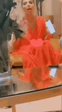 a woman in a red dress is sitting on a couch holding a phone