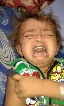 a little boy wearing a green garfield shirt is crying