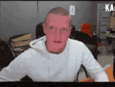 a man with a red face is sitting in front of a sign that says ka