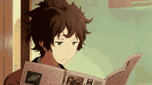 a boy is reading a newspaper with a picture of saturn on the front
