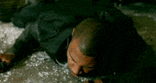 a man in a black suit is laying on the ground with blood on his face .