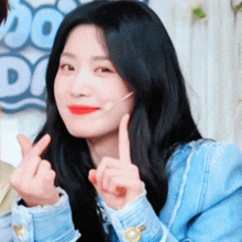 a woman in a blue jacket is making a heart with her hands