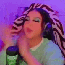 a girl wearing headphones is sitting in front of a microphone and making a funny face .