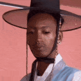 a man is wearing a hat and a blue vest .