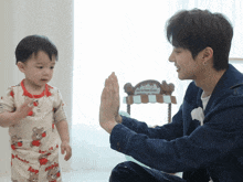 a man giving a baby a high five in front of a cotton candy cart