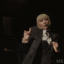 a woman in a suit is holding an umbrella with the letters ms visible in the corner