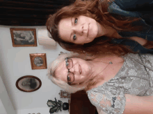 two women are posing for a picture in a room with pictures on the wall behind them