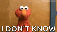 elmo from sesame street is holding a sign that says `` i don t know '' .