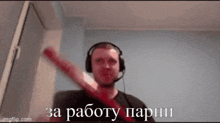a man wearing headphones and a microphone is holding a bat and says " za pabotu parhi "
