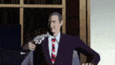 a man in a suit and tie is holding a gun in his hand .