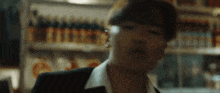 a man in a suit and white shirt is standing in front of a shelf with bottles of beer .