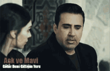 a man and a woman are looking at each other in a scene from a movie .