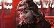 a woman with horns on her head is smiling and looking down .