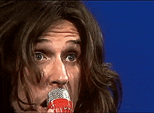 a close up of a person holding a microphone with a blue background