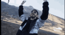 a man with his arms in the air standing in front of a mountain