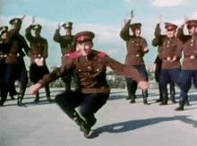 a group of men in military uniforms are dancing in a line