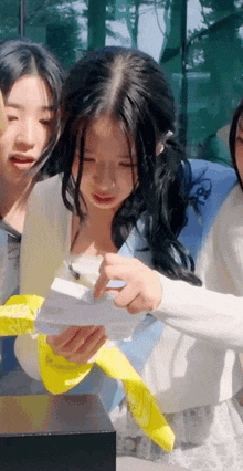 a girl is holding a piece of paper in her hands while standing next to another girl .