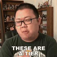 a man wearing glasses and a green shirt that says these are a-tier