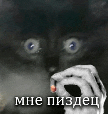 a black and white photo of a person 's hand holding a red object in front of their face with russian writing on the bottom