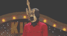 a man wearing a mask and a red shirt stands in front of a sign that says " king "