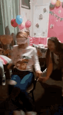 a group of people are sitting in a room with balloons and holding hands .