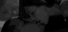 a black and white photo of a couple kissing .