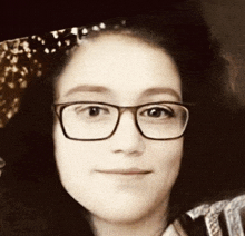 a woman wearing glasses and a headband smiles at the camera