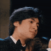 a young man in a tuxedo is hugging a woman