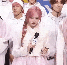 a woman in a pink dress is holding a microphone in front of a group of people .