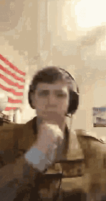 a man wearing headphones and a military uniform looks at the camera