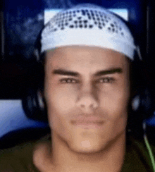 a man wearing headphones and a bandana on his head is looking at the camera .