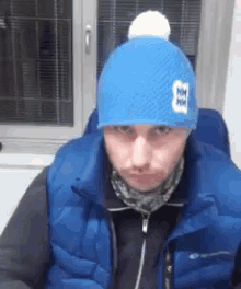 a man wearing a blue vest and a blue hat with the letter hm on it