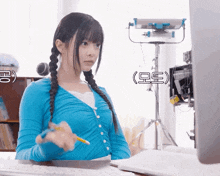 a girl in a blue sweater is sitting at a desk with a pencil in her hand