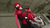a man in a red costume is holding a toy car in his hand