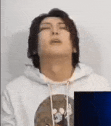a man wearing a white hoodie is making a funny face .