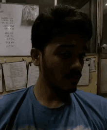 a man in a blue shirt is standing in front of a white board with numbers written on it